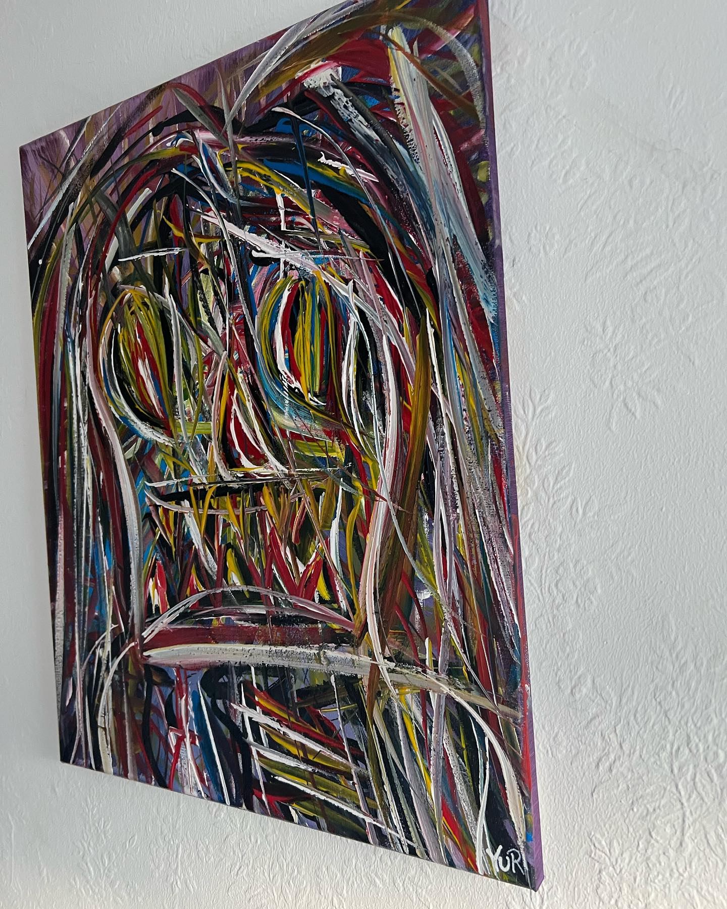 Abstract painting with multicolored brush strokes on a white wall